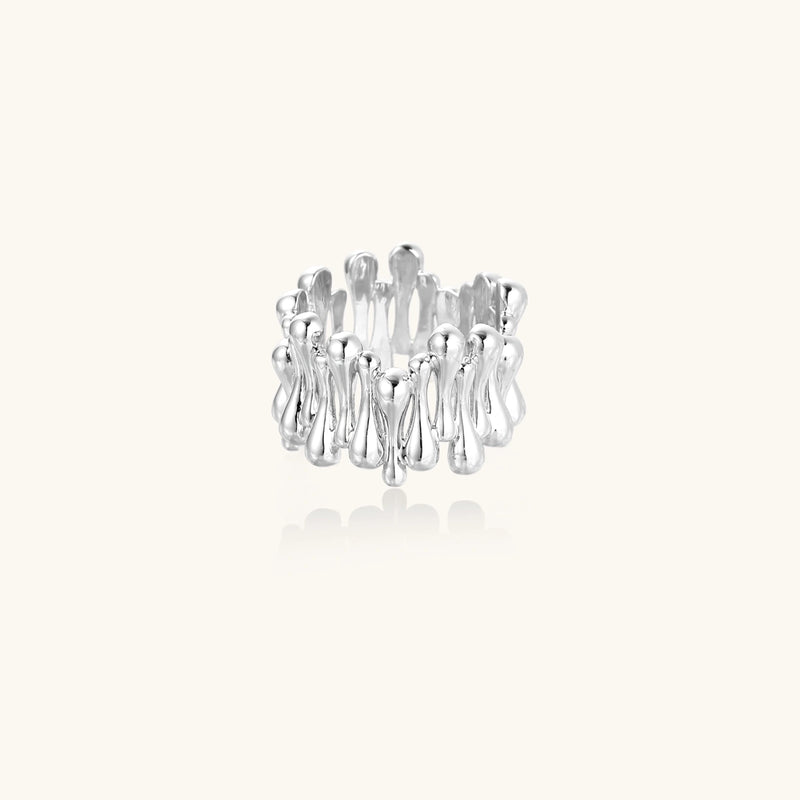 Wide band ring with sculptural wave ripples in polished white gold plated eco-brass on cream background