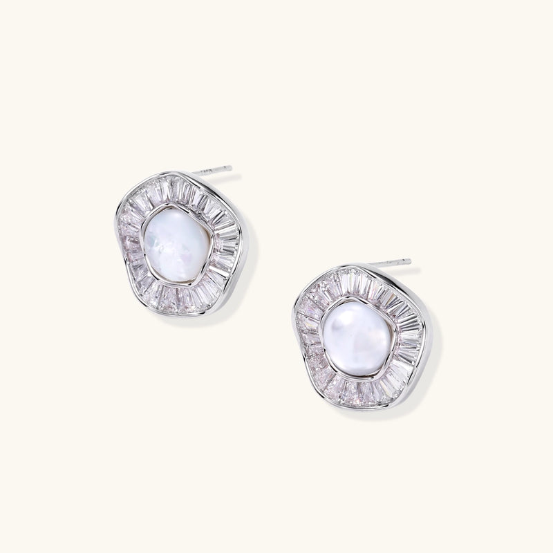 White gold-plated stud earrings with iridescent pearl centers surrounded by baguette crystal halos on white background.